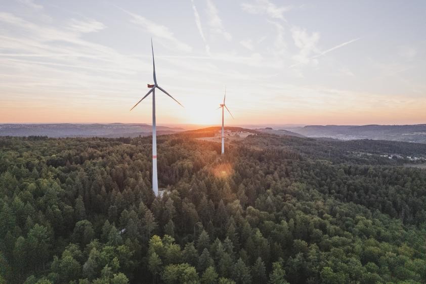 zwei Windräder in Waldgebiet bei Sonnenuntergang