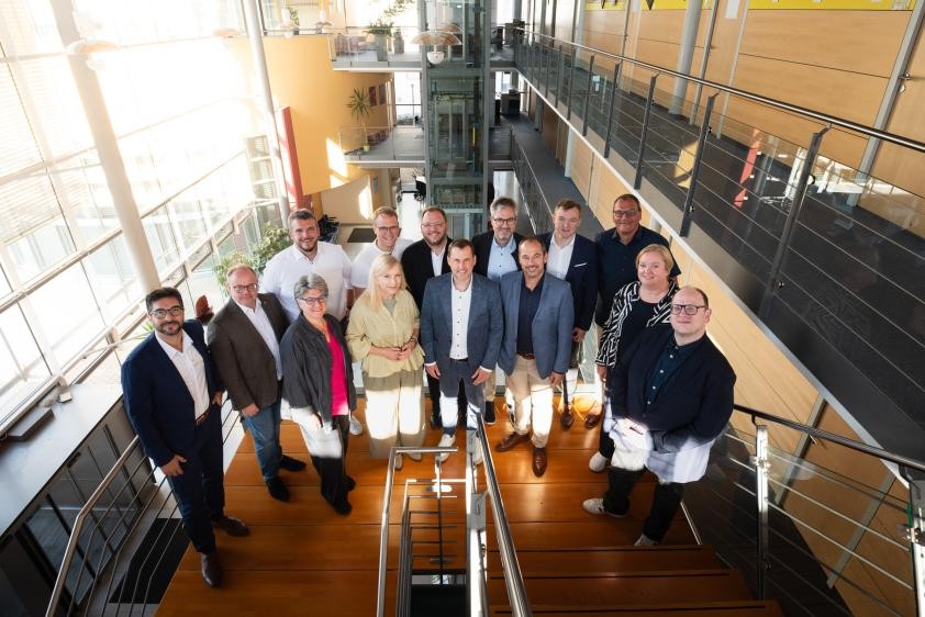 Gruppenbild auf einer Treppe während der Veranstaltung "Pflege im Takt der Region"